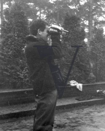 B&W photo, man looking through 16mm film camera.