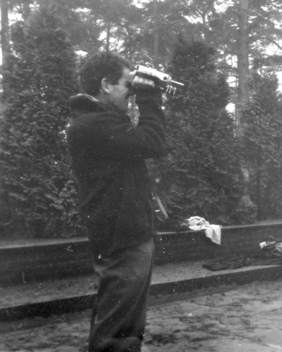 B&W photo, man looking through 16mm film camera.