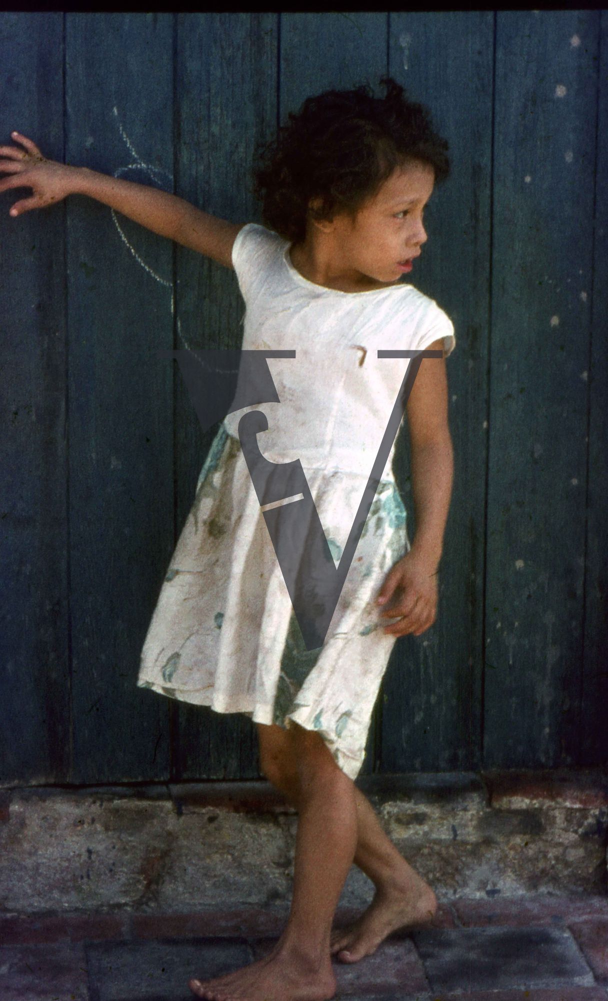 Mexico, Little girl holds hand out by blue door.