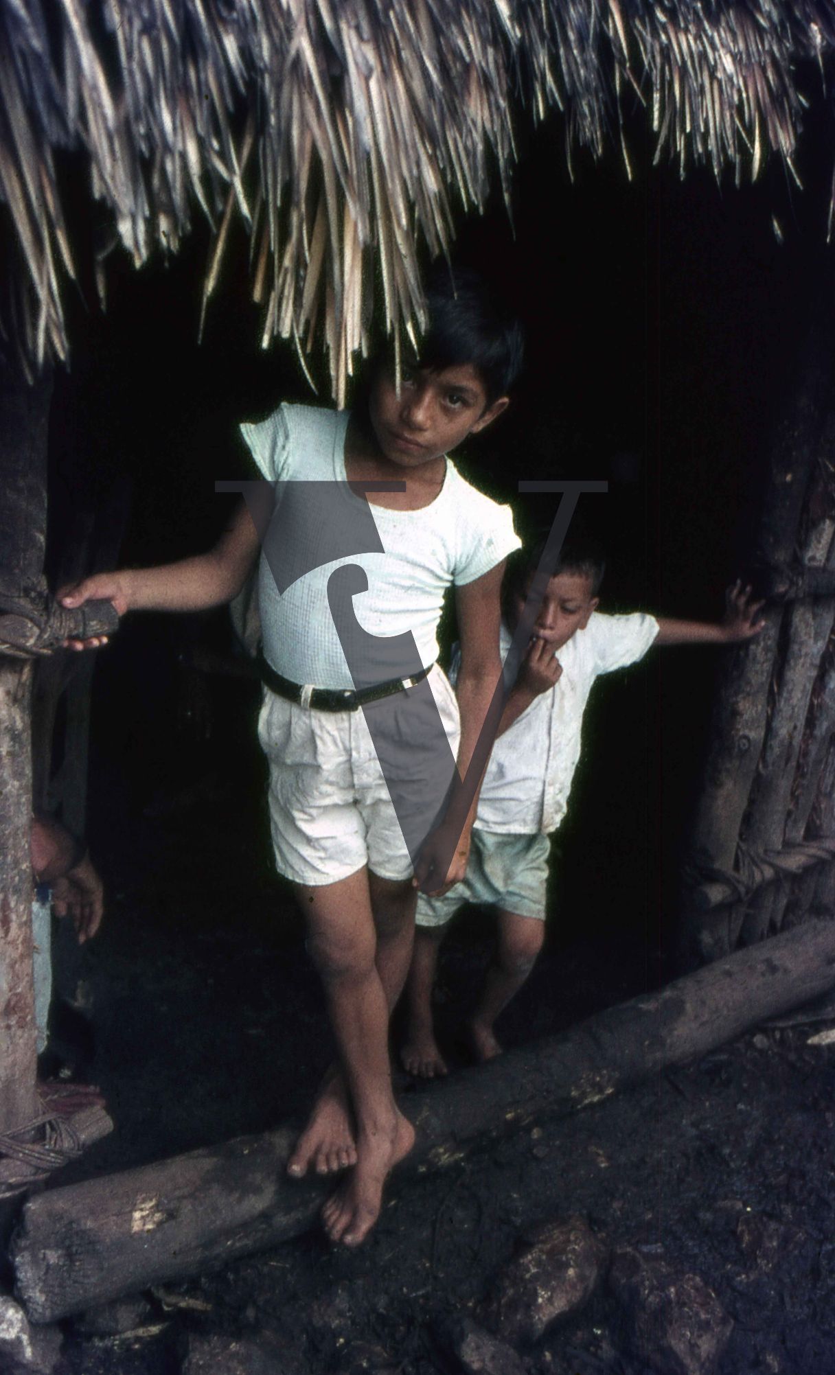 Mexico, Two boys emerging from house.