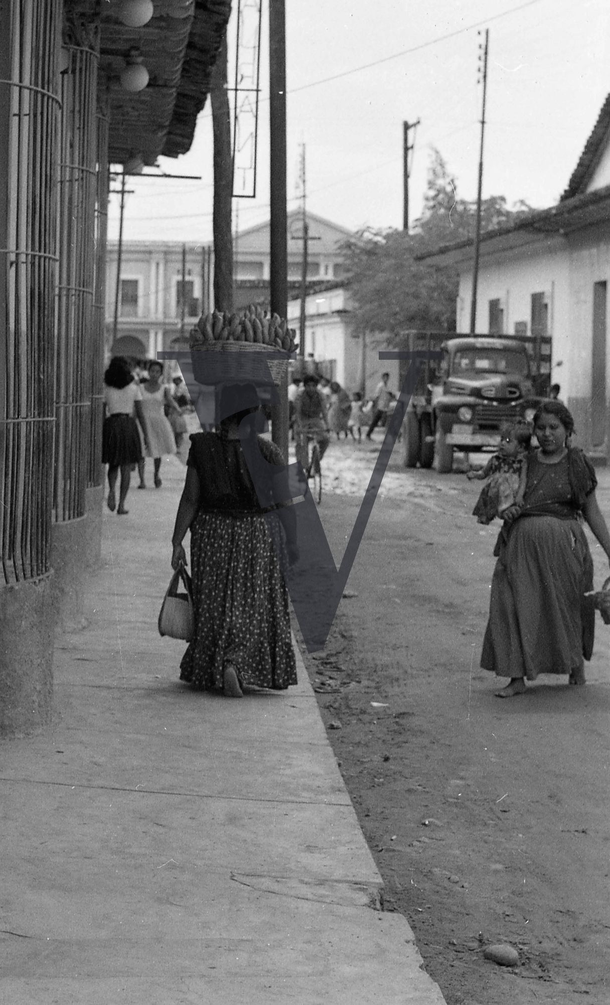 Mexico, Street view, woman carrying bananas on head.