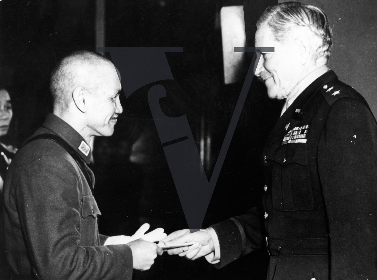 China, Chiang Kai-shek exchanging a document with General Patrick J. Hurley, smiling, profile, candid, mid-shot.
