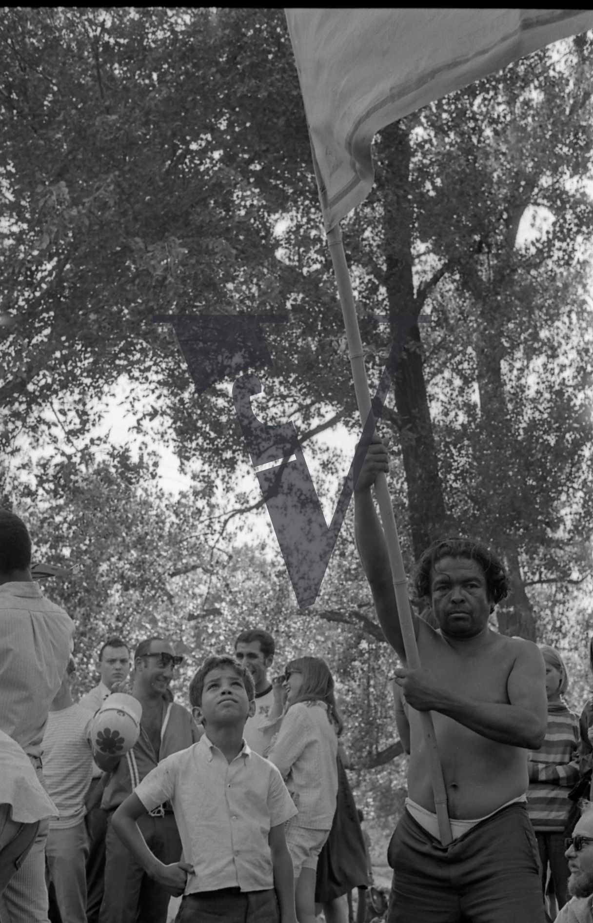 Chicago, Anti-war rallies in Lincoln Park, man with flag stares at camera, boy looks on.