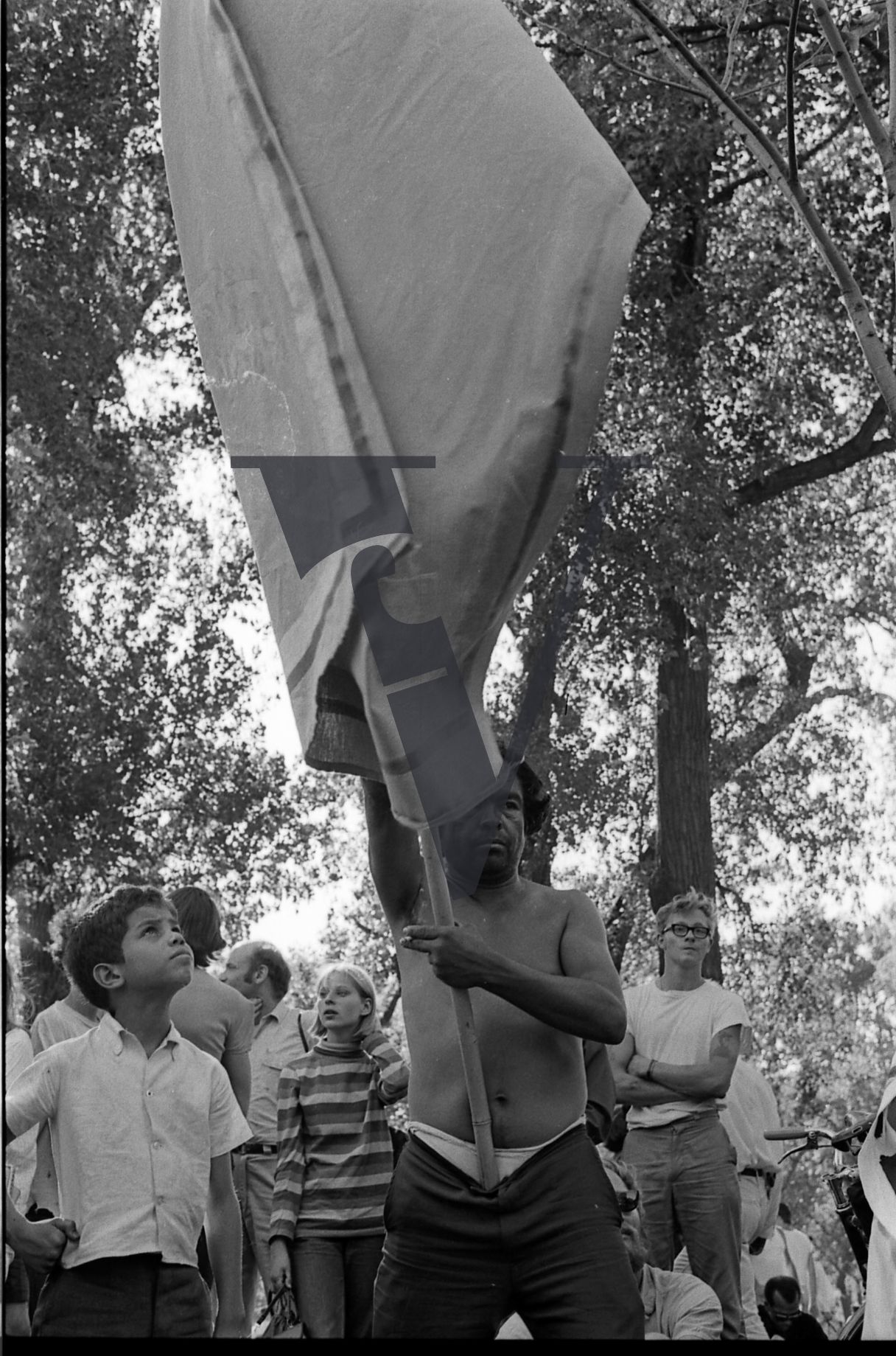 Chicago, Anti-war rallies in Lincoln Park, man with flag stares at camera, boy looks on.