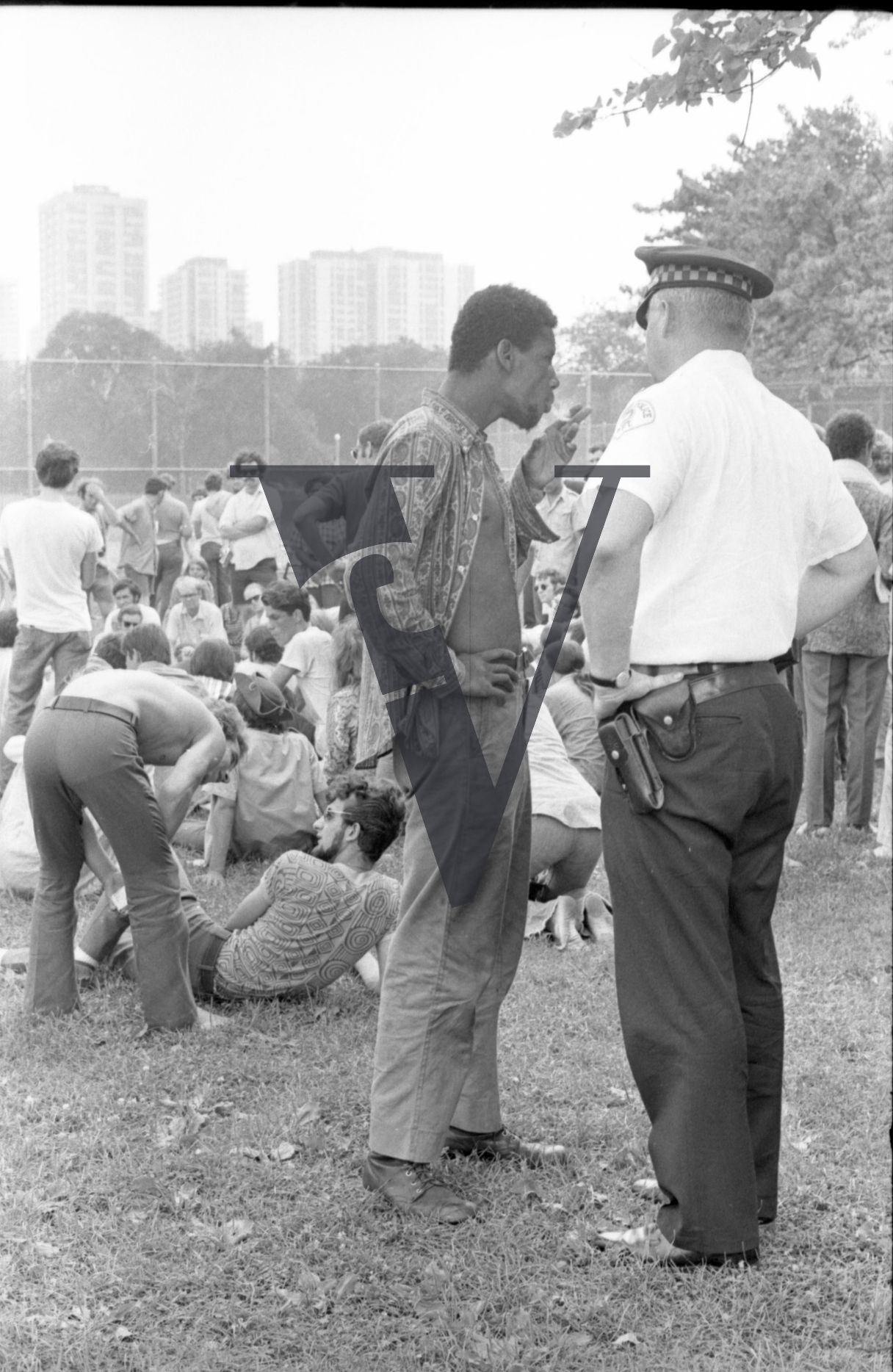 Chicago, Anti-war rallies in Lincoln Park, man talks to to police officer, smokes cigarette.