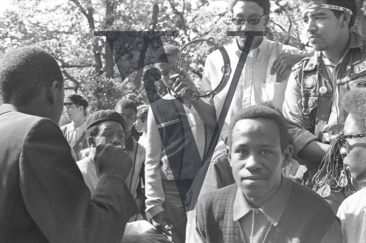 Chicago, Anti-war rallies in Lincoln Park, black youths look at camera, boy plays tambourine.