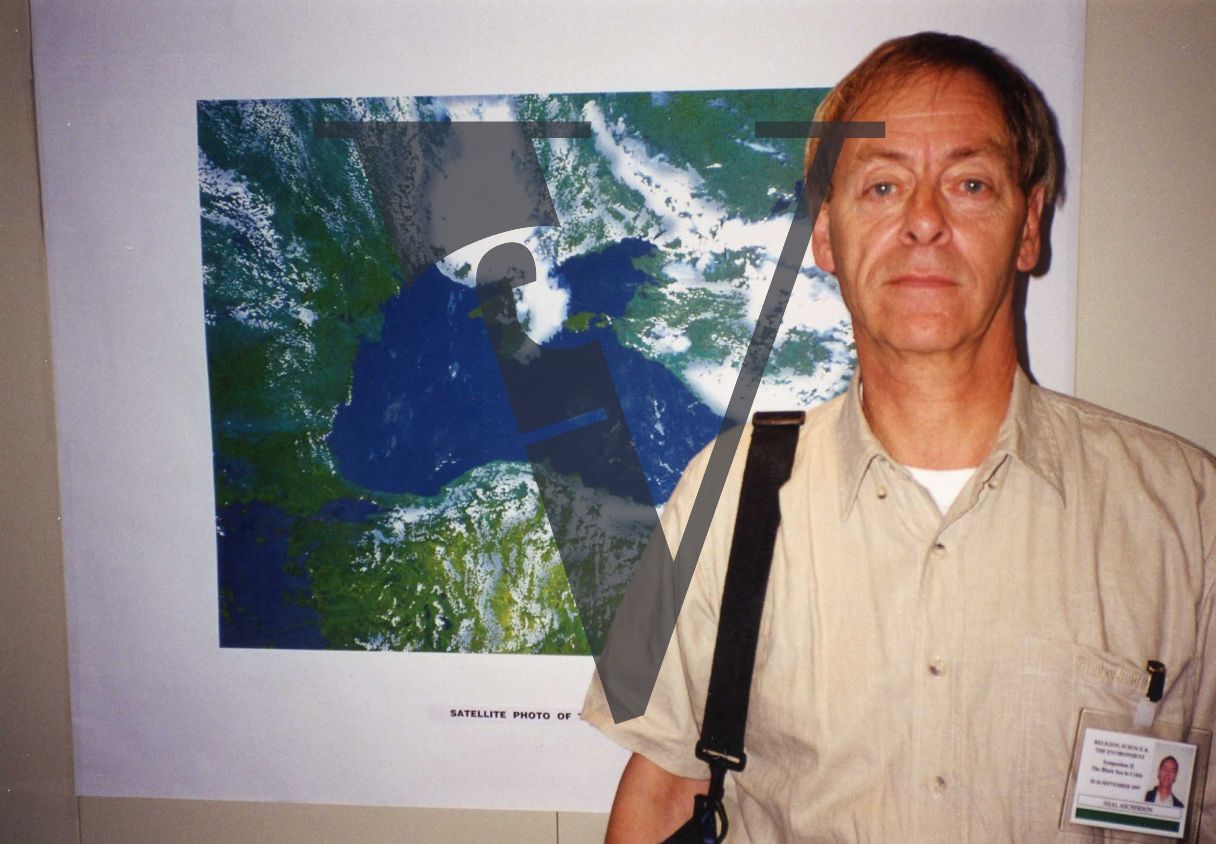Neal Ascherson, portrait, in front of satellite imagery.