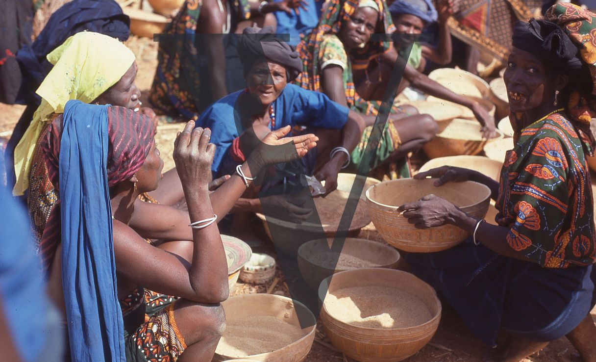 Nigeria, women with bowls sit talking.