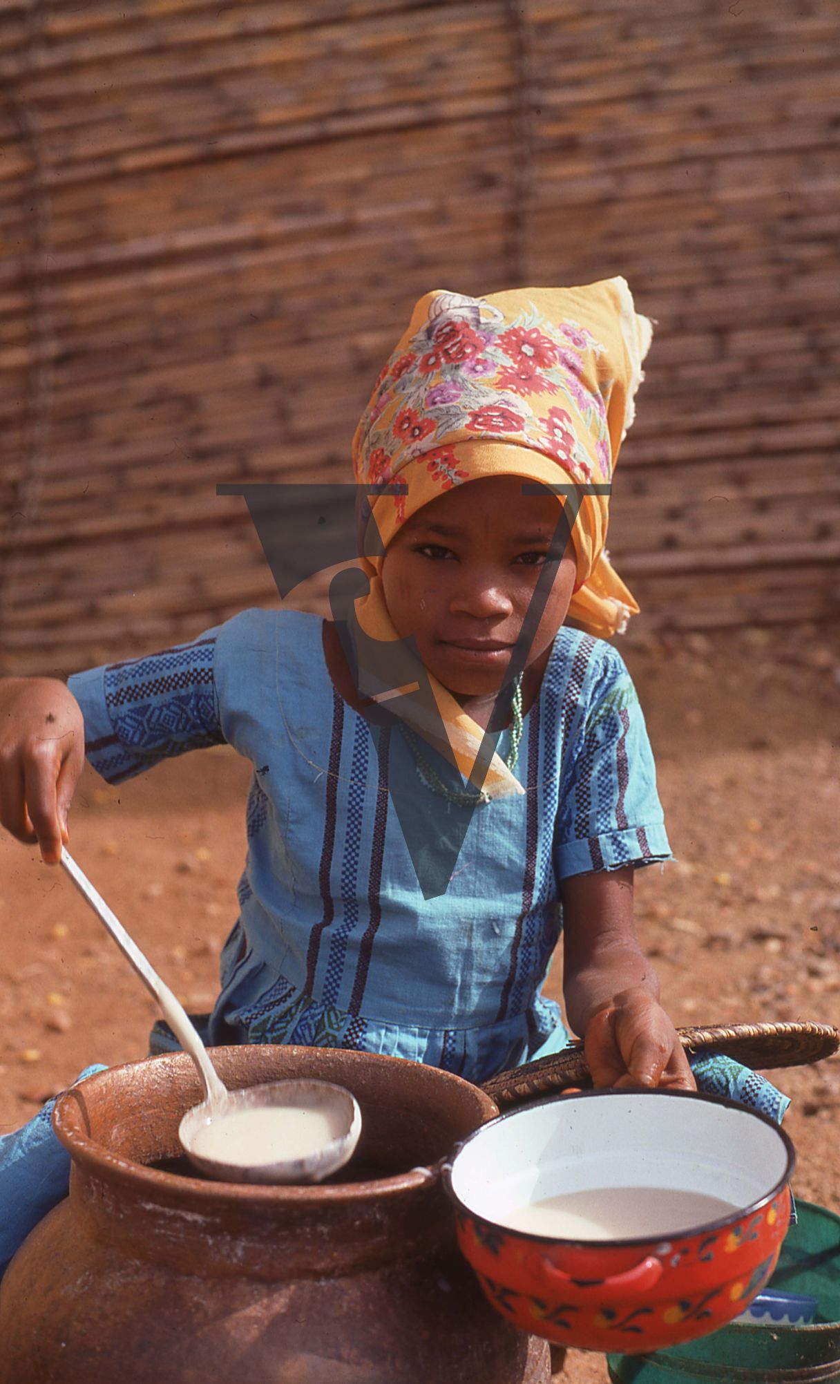 Nigeria, girls spooning food into dish.