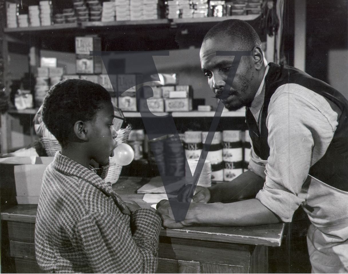 African Jim, boy blowing bubble gum in shop.