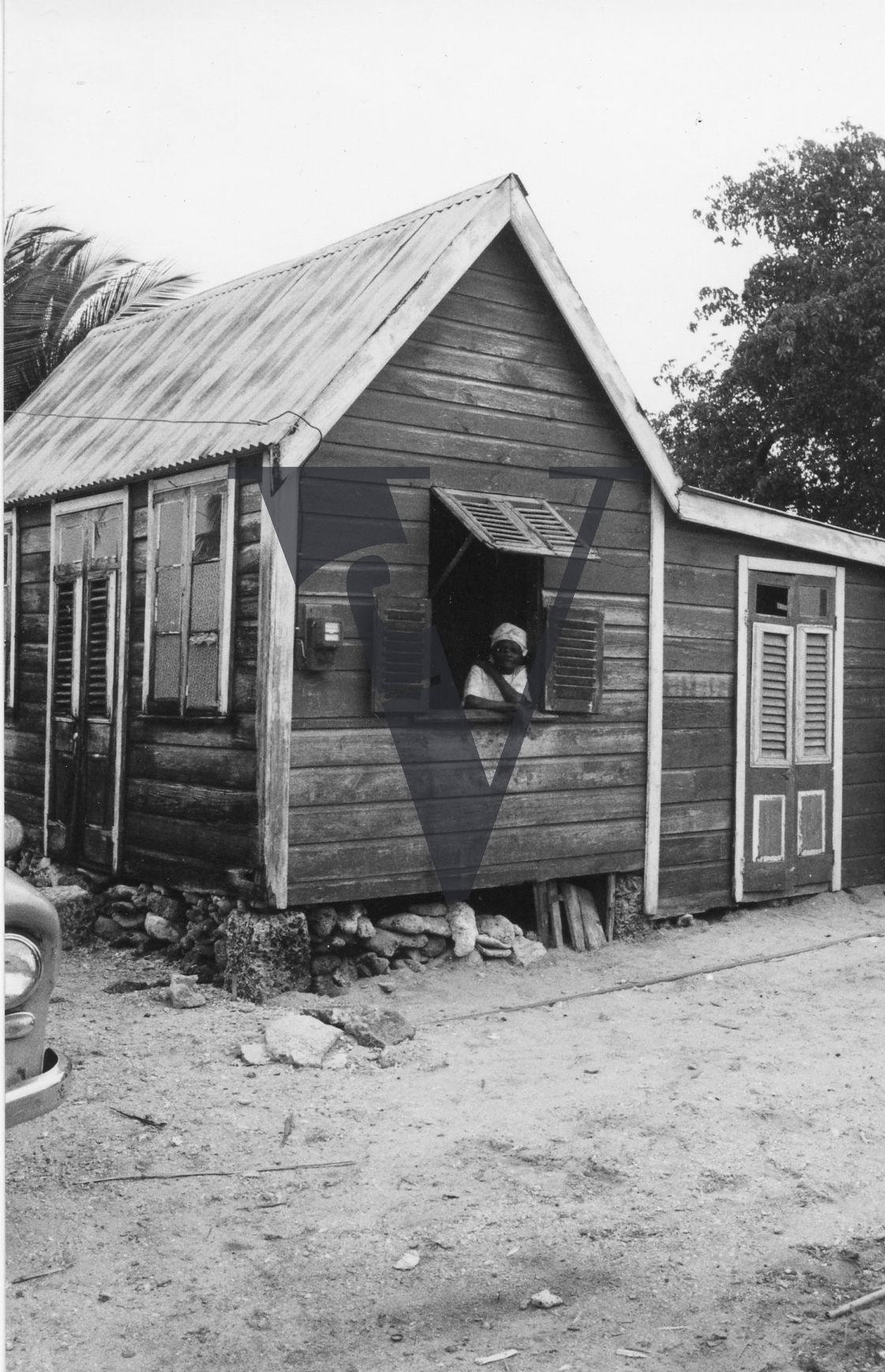 Barbados, wooden house. woman outside window.
