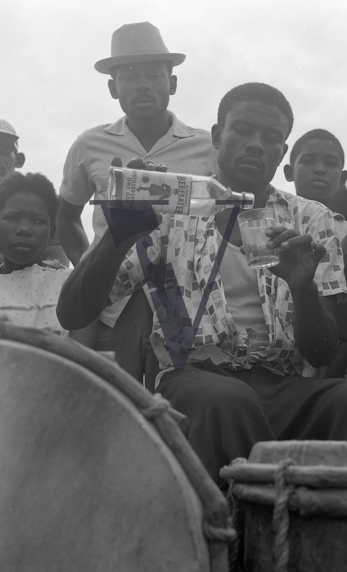 Belize, Man pours Beefeater Gin bottle into glass, man watches.