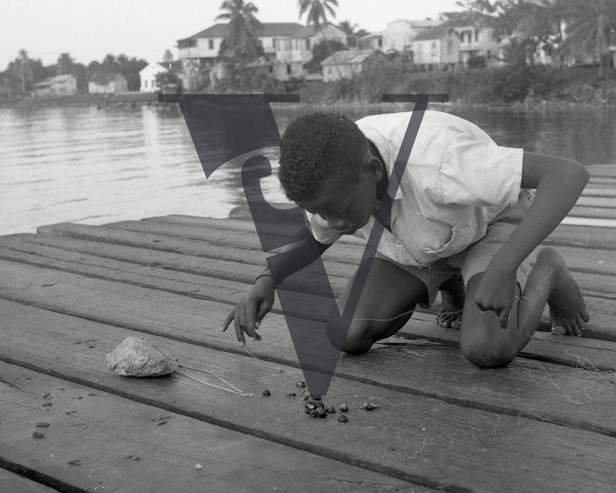 Belize, River, boy with fishing line and mollusc shells.