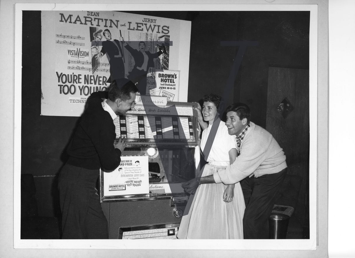 Jerry Lewis with young woman and man, smiling, Brown's Hotel, jukebox.