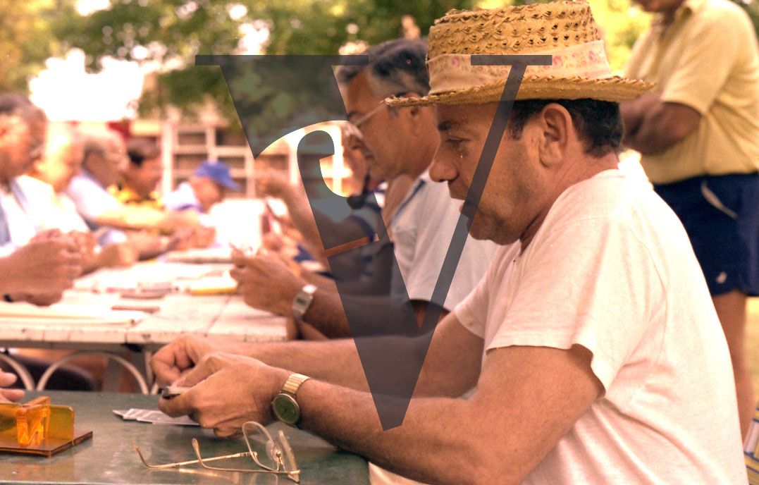 Bungalow colony, people playing cards, exterior, mid shot.