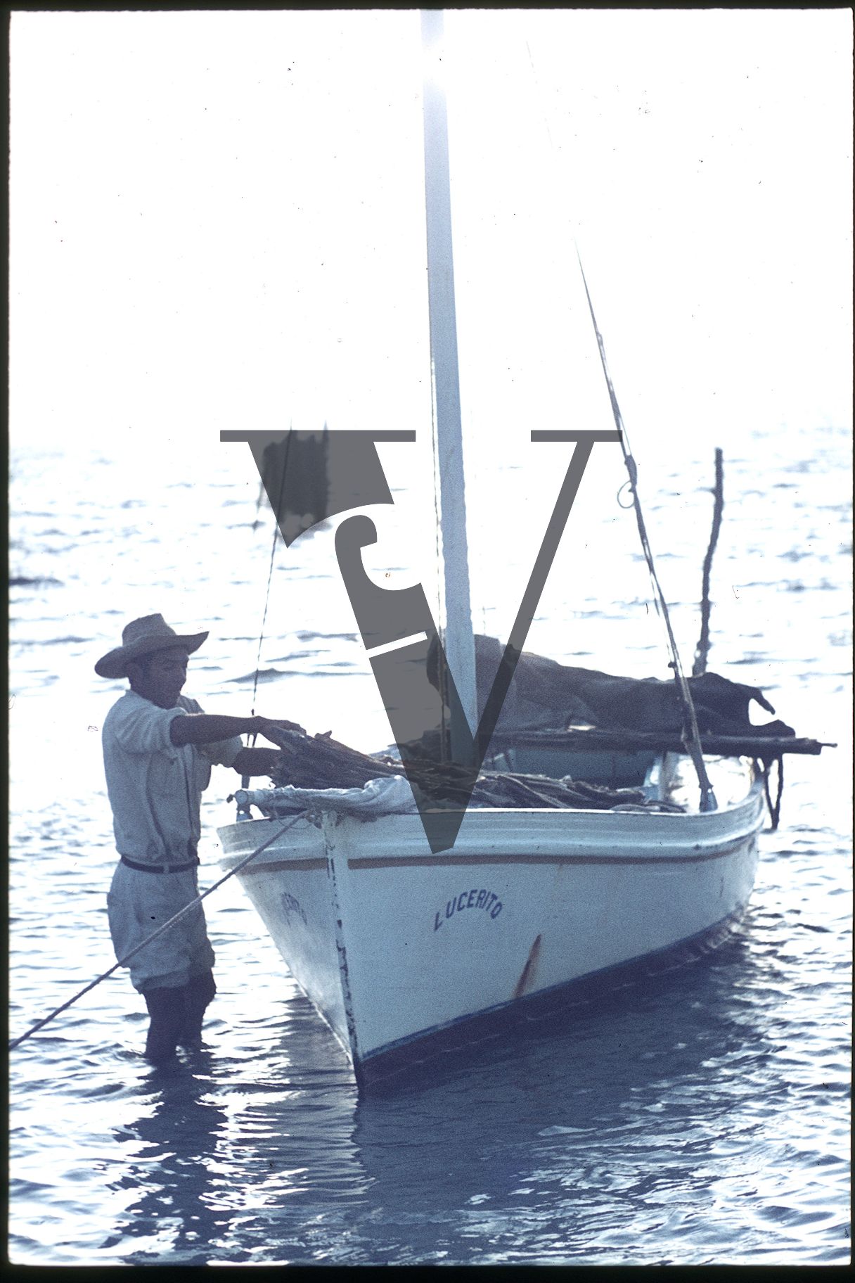 Belize, Ambergris, Man loads small boat in the ocean.