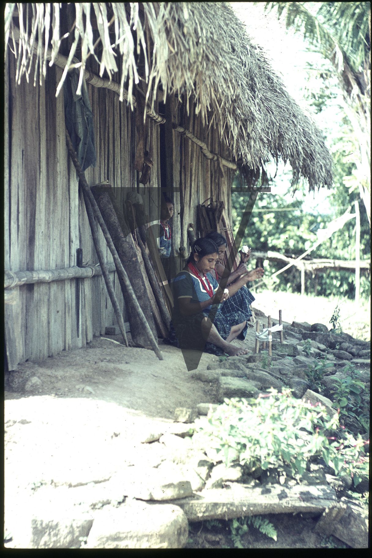 Belize, Girls sit underneath hut roof, Kekchi.