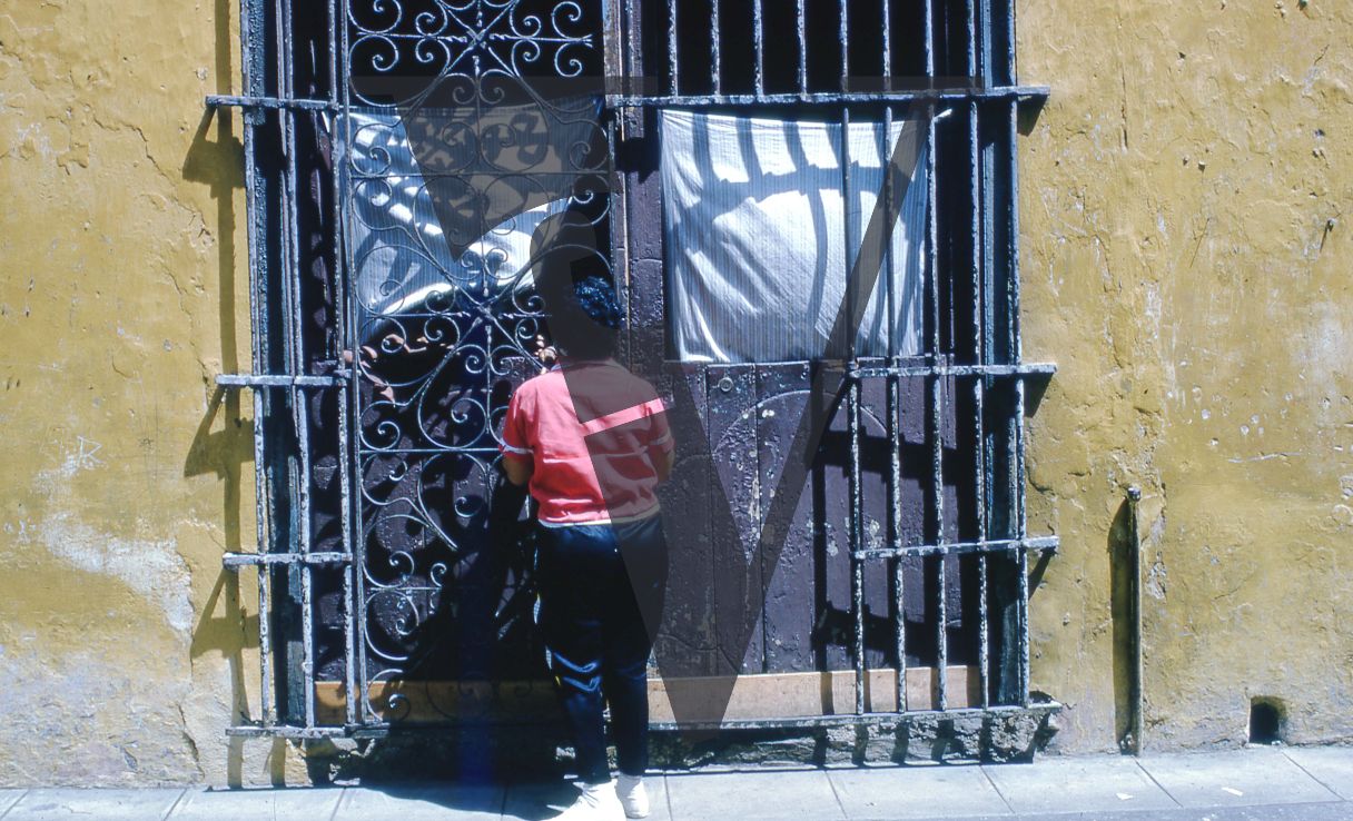 Cuba, Havana, May 1st, woman outside iron gate.