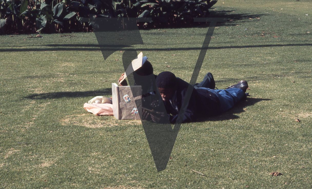 South Africa, Johannesburg, Joubert Park, two people lying on grass.