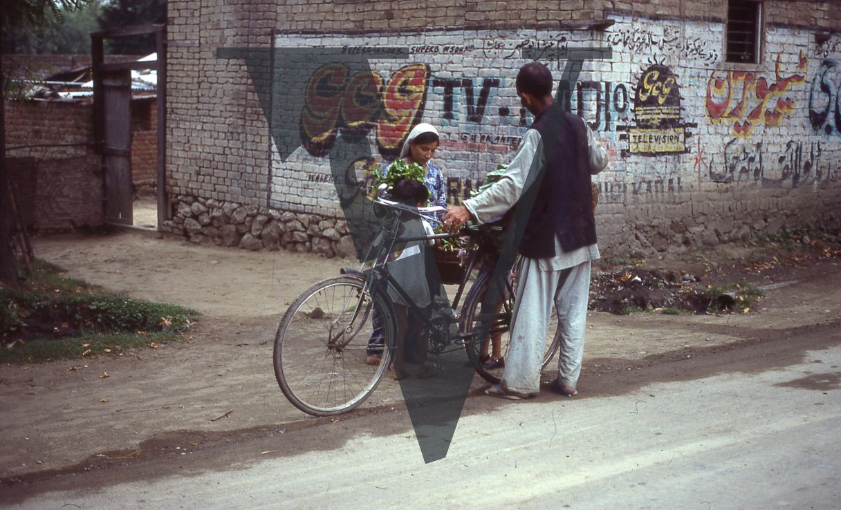 Kashmir, Man holding bicycle with family.