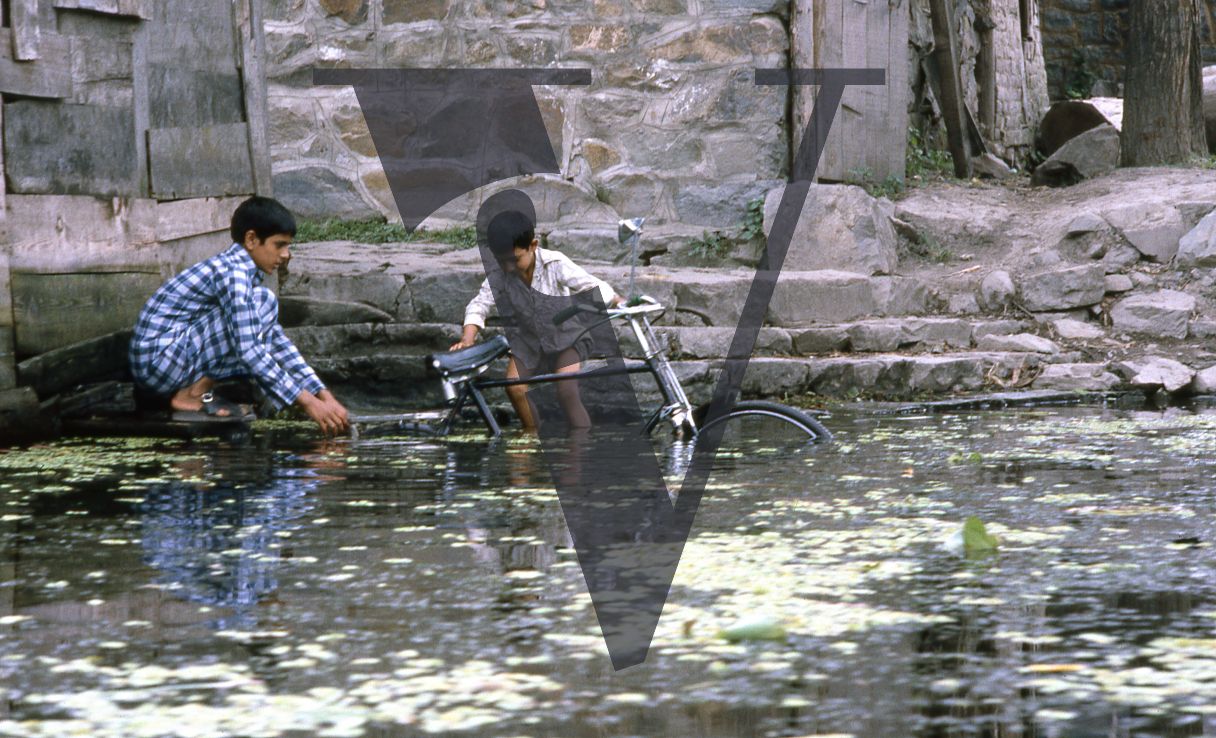 Kashmir, Boys washing bike in lake.