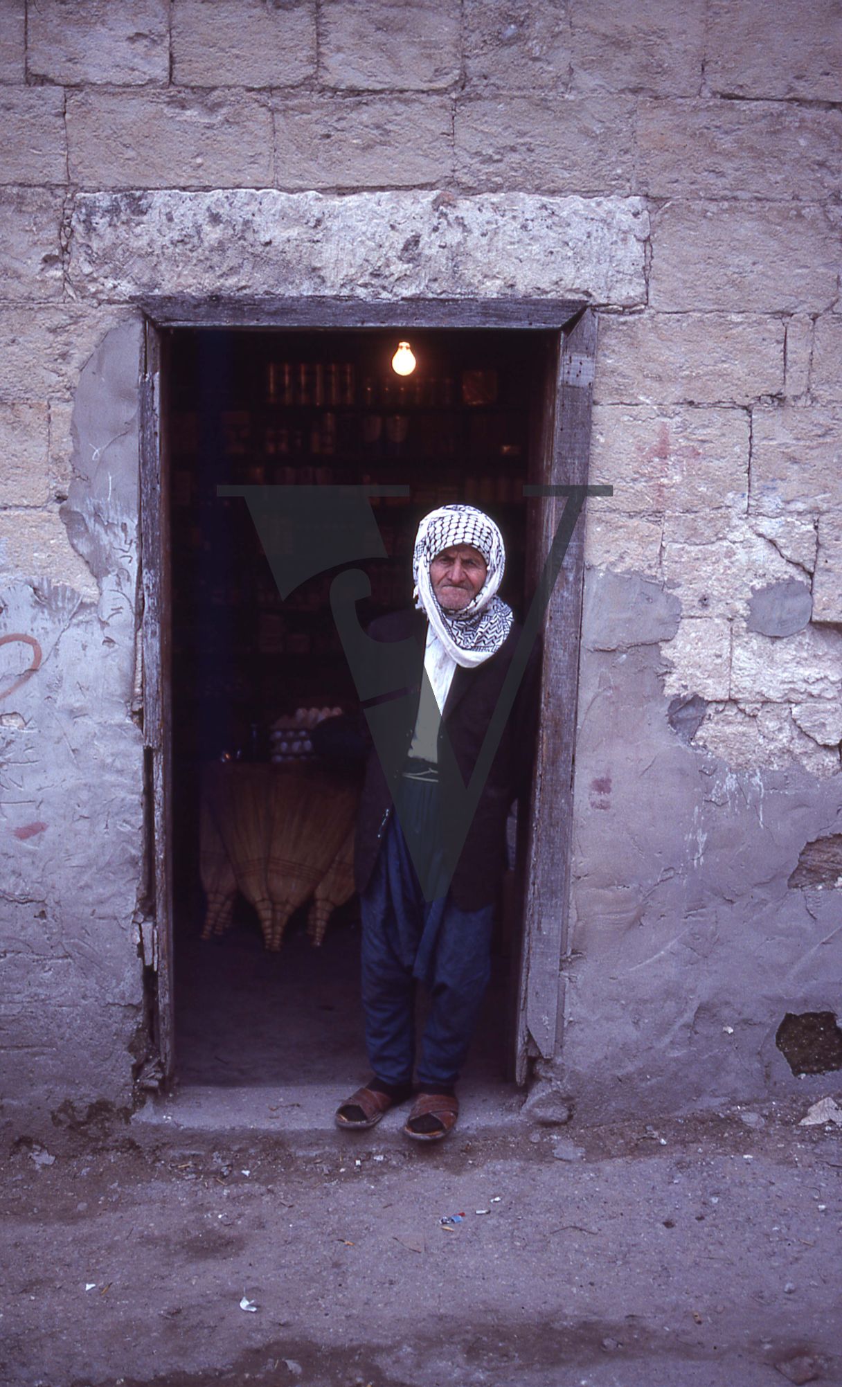 Lebanon, South of Beirut, man in keffiyeh stands outside shop, portrait.