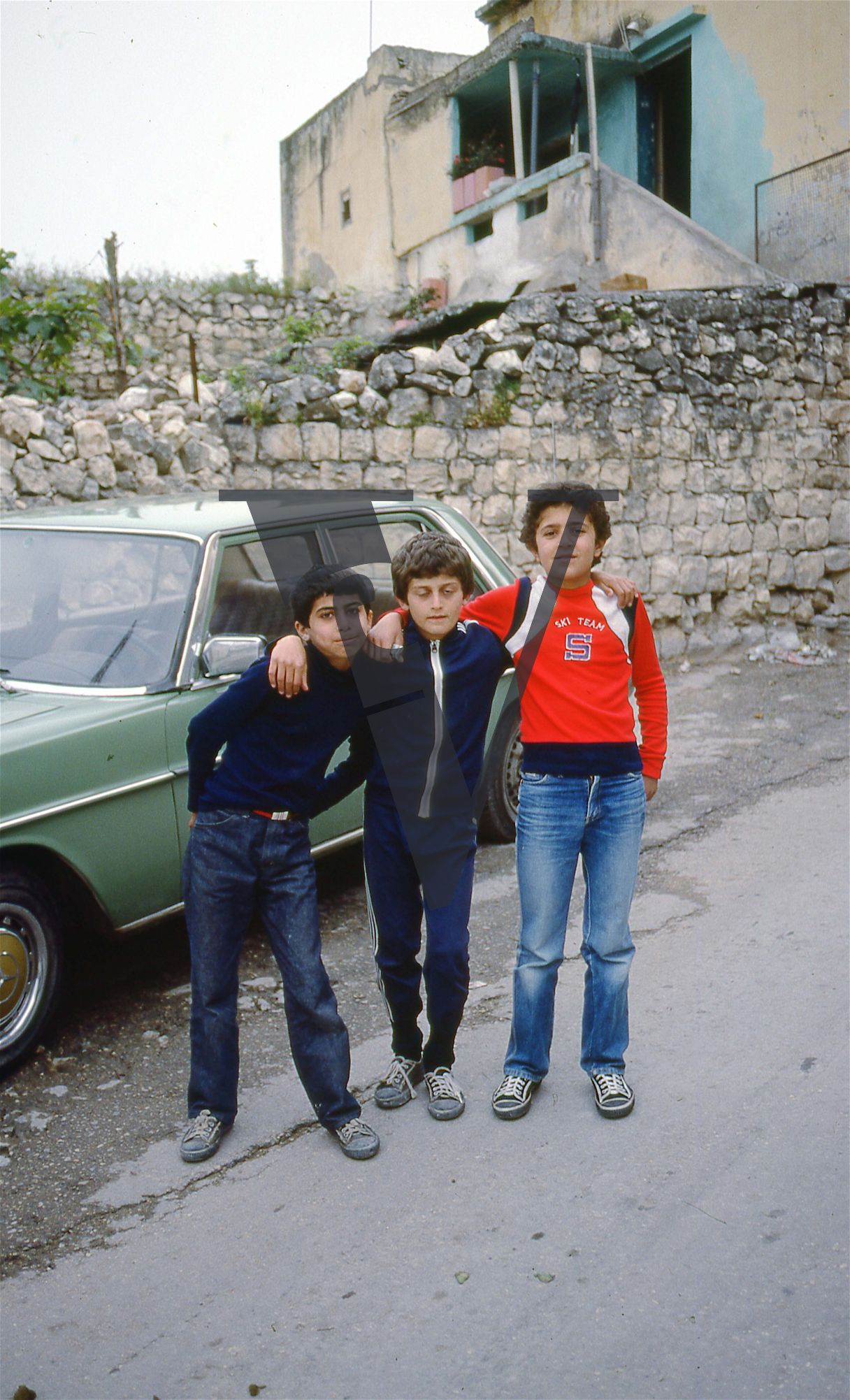 Lebanon, South of Beirut, three young boys pose in front of green car, portrait.