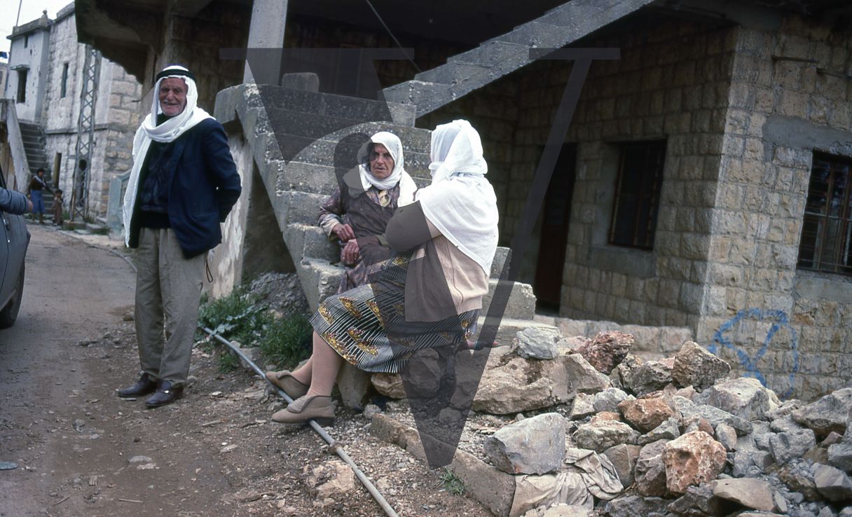 Lebanon, Beirut, Man in keffiyeh, women in headscarf, war damage and rubble.