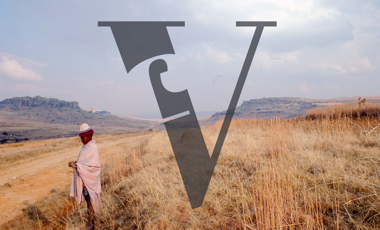Lesotho, boy in blanket and striped hat, portrait, wide shot.