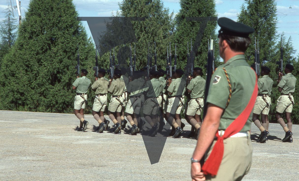 Rhodesia, Rhodesian African Rifles, sergeant, red sash, soldiers parading, military training area, wide shot.