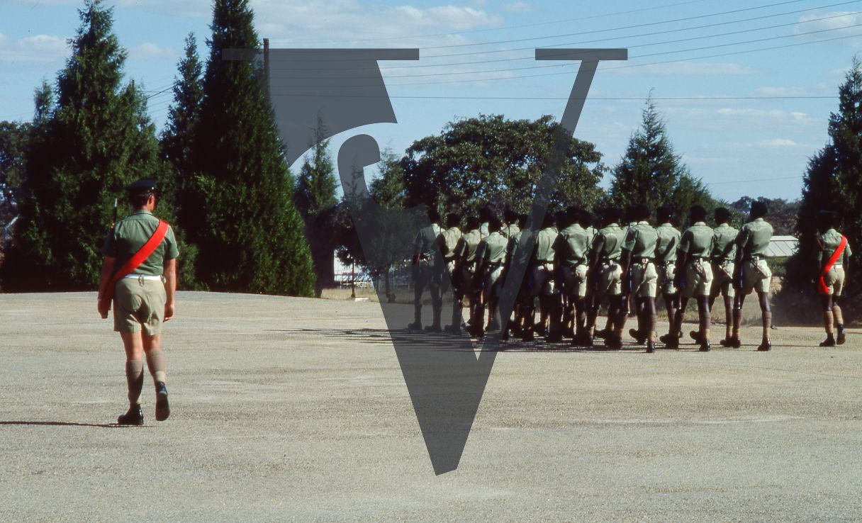 Rhodesia, Rhodesian African Rifles, sergeant, red sash, soldiers marching, military training area, wide shot.