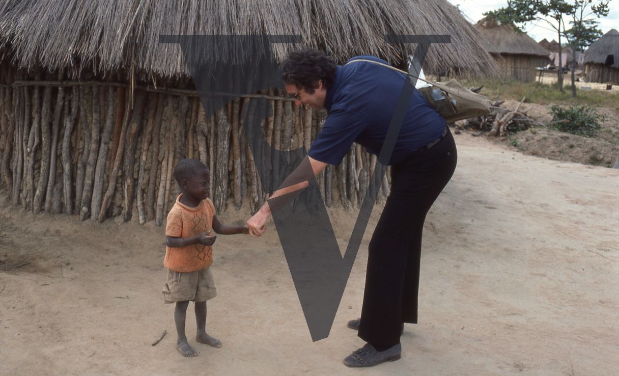 Rhodesia, “protected village”, Barry Callaghan with small boy, full shot.