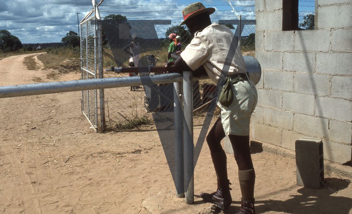 Rhodesia, “protected village”, armed guard, rifle, barbed wire fence.