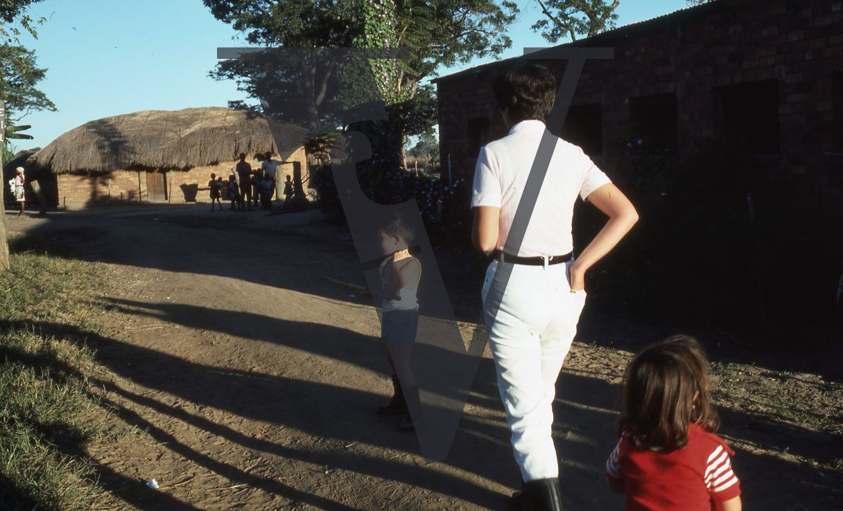 Rhodesia, cattle farm, farm owner with her children, farmworkers, huts, shadows.