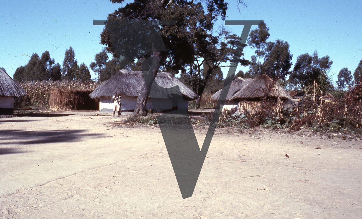 Rhodesia, tobacco farm, rondavels, woman and child, long shot.