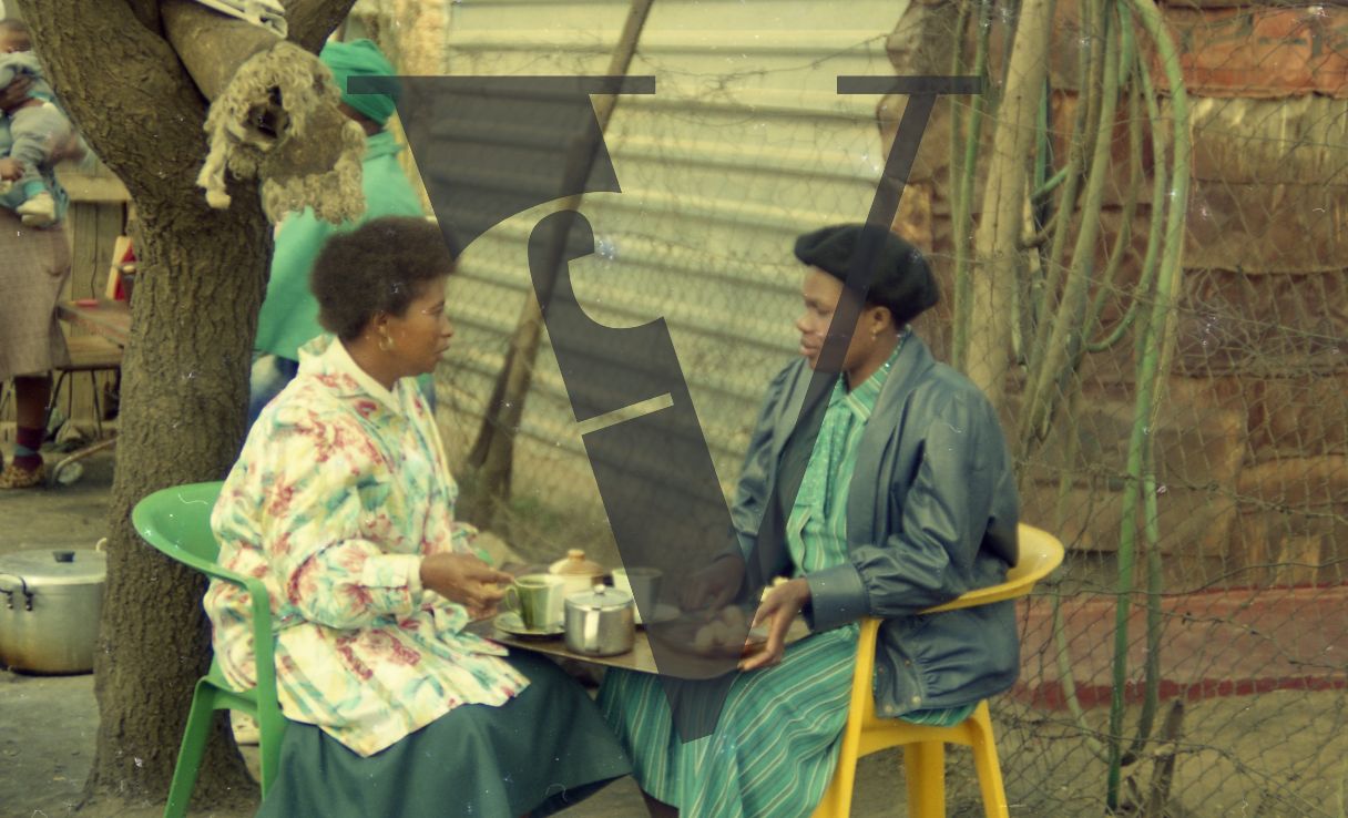 South Africa, shanty town, two women in conversation drinking tea.