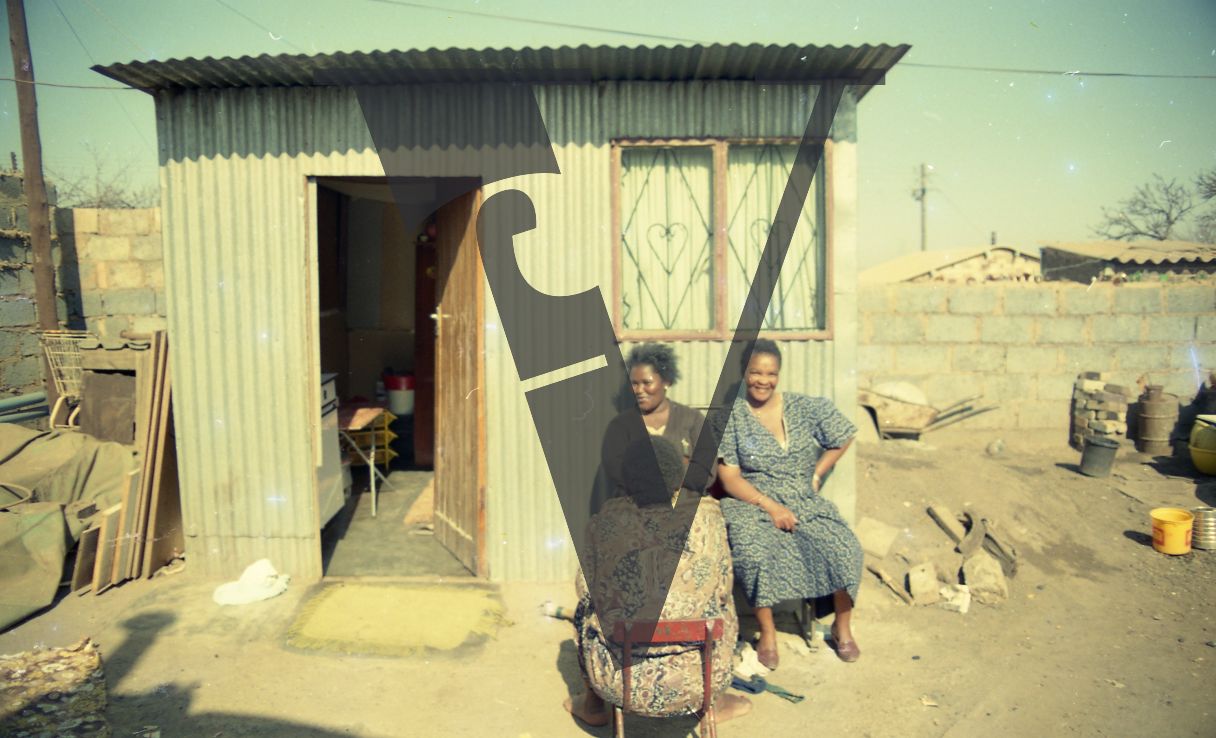 South Africa, Soweto, three women, smiling, exterior, tin shack.