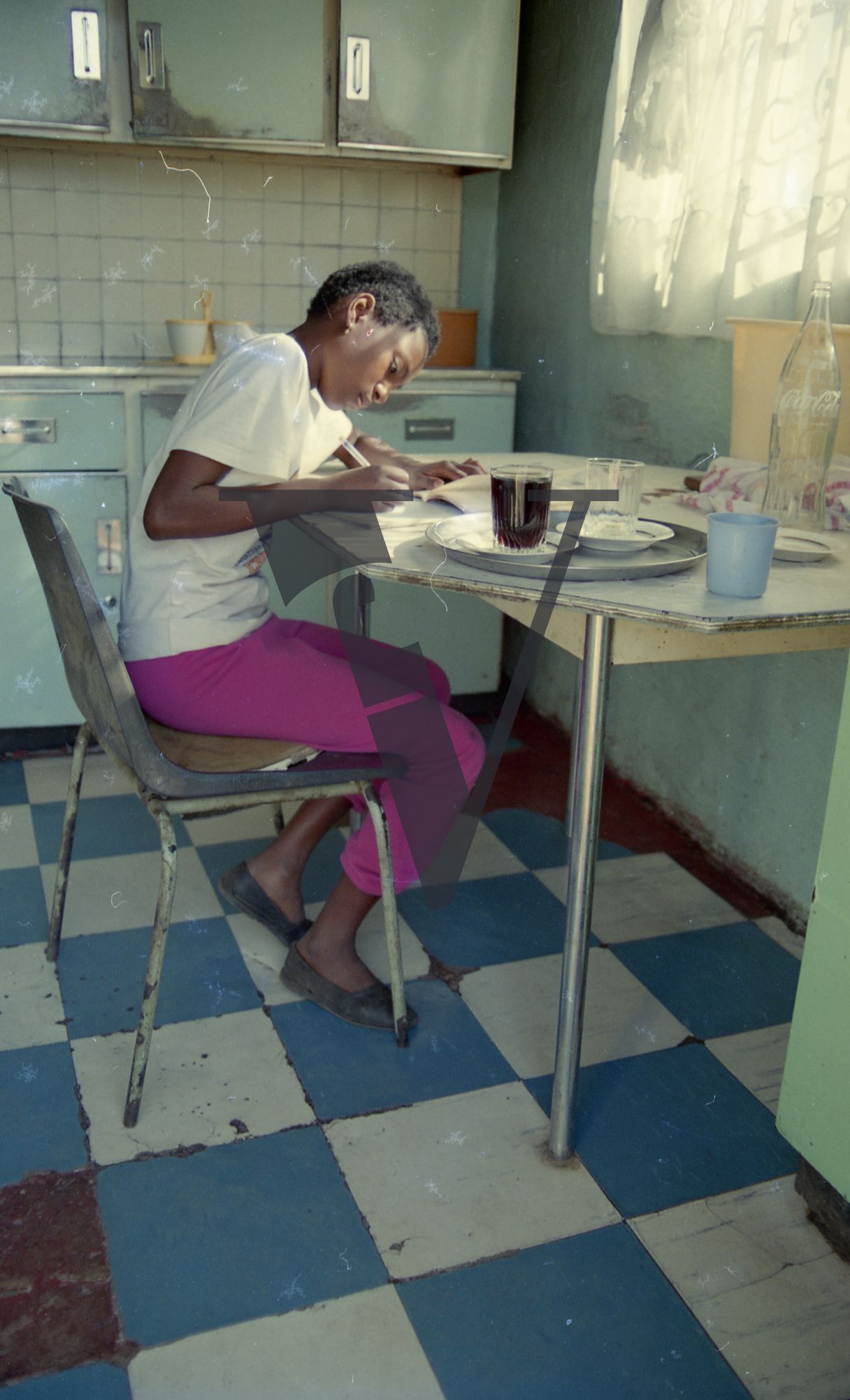 South Africa, Soweto, township, girl doing homework at kitchen table.