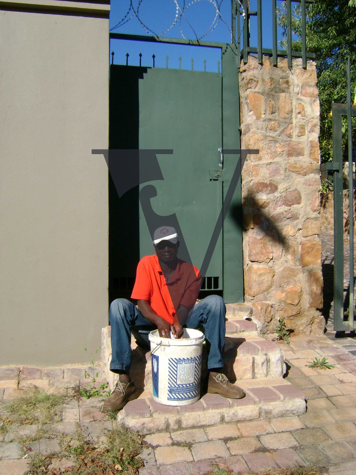 Johannesburg, man seated outside gated house.