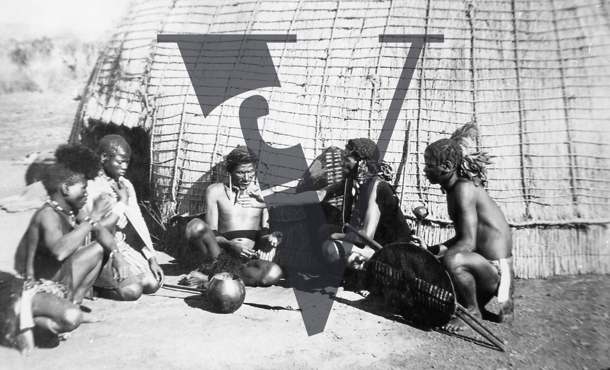South Africa, ‘Zululand’ film, production still, Indigenous people seated, exterior, full shot.
