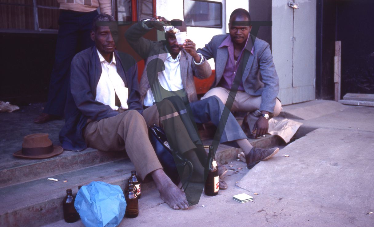 South Africa, Transkei, men sitting on steps, drinking.