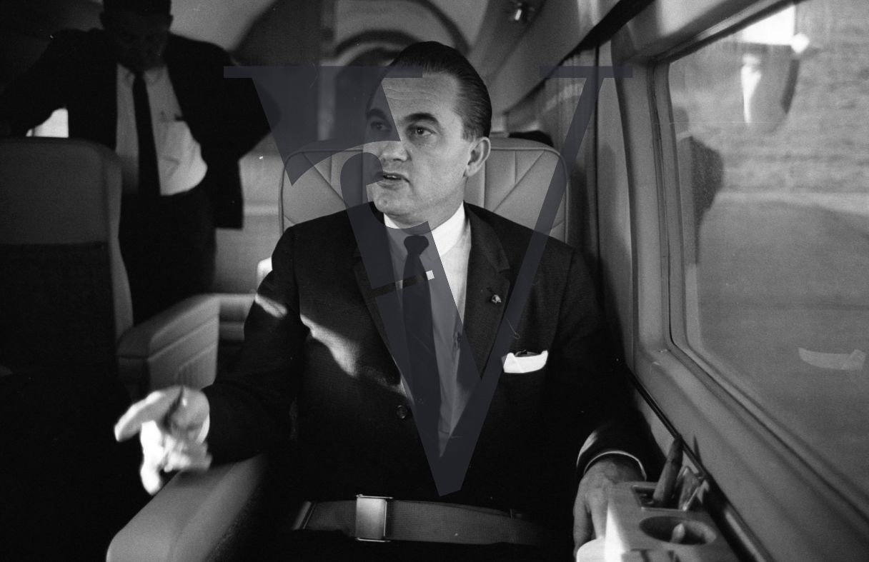 Governor George Wallace, on board plane, portrait, pointing.