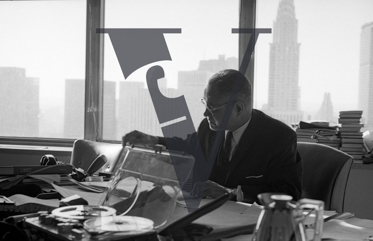 Ralph Bunche, portrait, writing, political scientist, diplomat, at desk, Empire State Building in background.